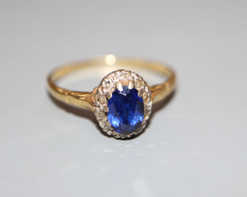 An 18ct, synthetic sapphire and diamond set oval cluster ring, size T, gross 3.2 grams.